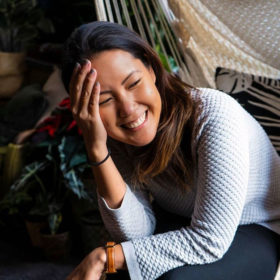 Garden of Alice customer Shanti laughing and looking down while holding her face