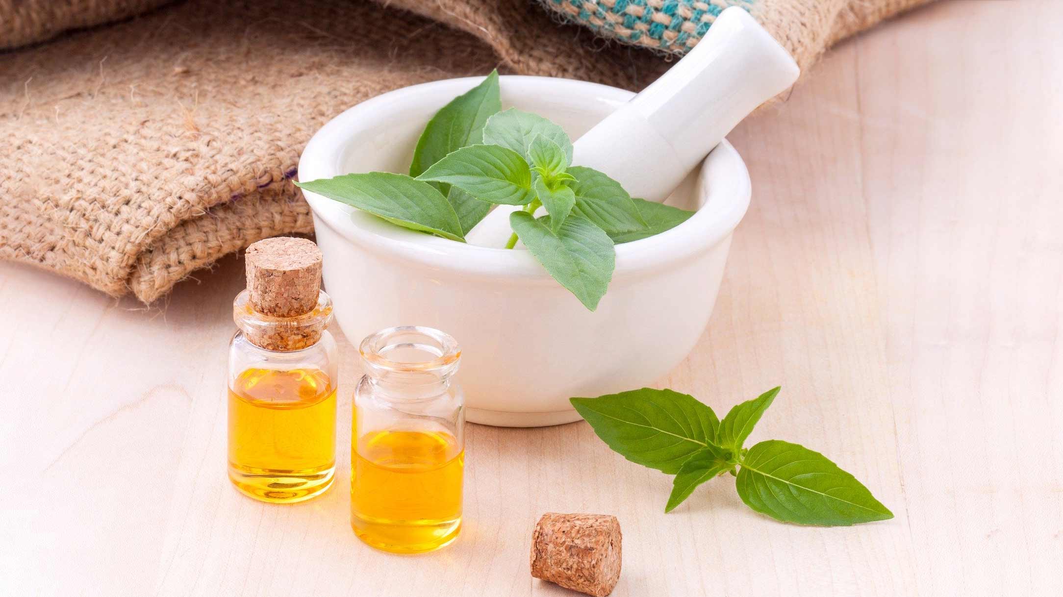 Aromatherapy essential oils in bottles next to a mortar